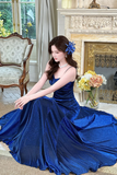 Woman in a blue evening gown sitting in a room with decorative elements.