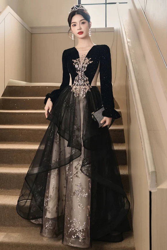 Woman in a black and silver evening gown standing on a staircase.