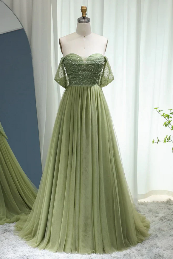 Green evening gown on a mannequin against a white curtain background