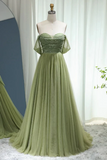 Green evening gown on a mannequin against a white curtain background