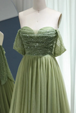 Green evening gown with beaded top on a mannequin against a neutral background