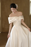 Woman wearing an off-shoulder white wedding dress with a blurred background