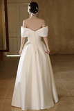 White off-shoulder wedding dress with a plain background
