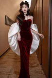 Woman in a red velvet dress with white wings in an indoor setting