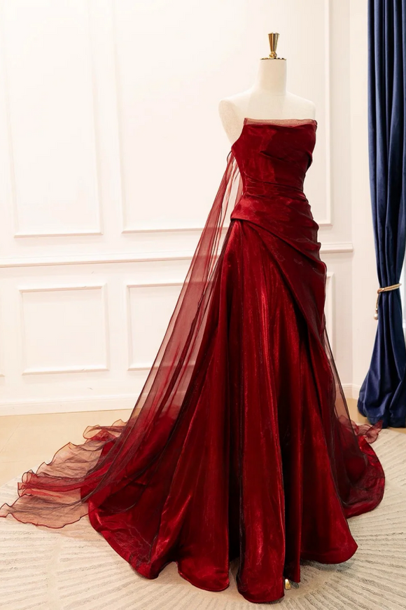 Red strapless evening gown on a mannequin against a white wall.