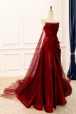 Red strapless evening gown on a mannequin against a white wall.