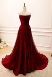 Red evening gown on a mannequin against a white wall.