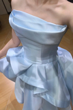 Light blue strapless dress with ruffled layers on a wooden floor.