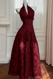 Burgundy lace dress on a mannequin against a white wall.