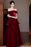 Woman wearing a burgundy off-shoulder evening gown with ruffled details.