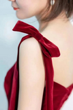 Close-up of a person wearing a red velvet garment with a bow detail on a light background