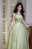 Woman in a light green evening gown standing indoors.