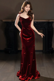 Woman wearing a red velvet evening gown in a dimly lit room.