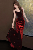 Woman in a red and black evening gown against a textured wall.