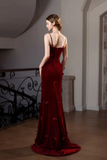 Woman in a red evening gown standing in an elegant interior setting.