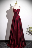 Red evening gown on a mannequin against a white wall.