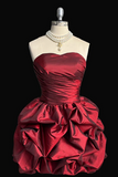 Red strapless dress on a mannequin with pearls against a black background