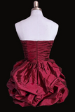 Red strapless dress with a full skirt on a mannequin against a black background