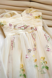 Cream-colored dress with floral and butterfly embroidery on a beige background