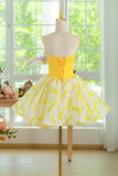 Yellow dress with floral pattern on a mannequin in front of a window with greenery.