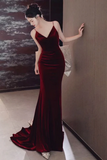 Woman in a red evening gown standing against a neutral wall.
