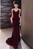 Woman wearing a burgundy velvet evening gown indoors.