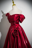 Red evening gown with floral details on a mannequin against a plain background