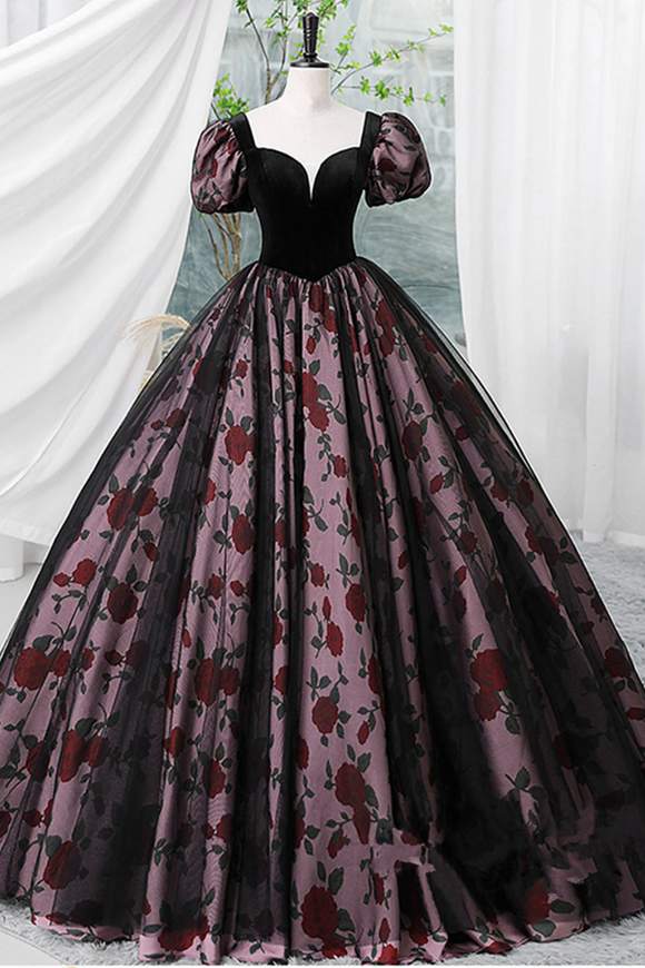 Black and red floral ball gown on a mannequin against a white curtain background