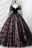 Black and red floral ball gown on a mannequin against a white curtain background