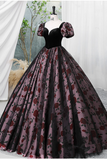 Black and red floral ball gown on a mannequin against a white curtain background