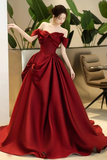 Red evening gown worn by a model with indoor plants in the background