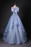 Light blue evening gown with a large bow on a mannequin against a dark background