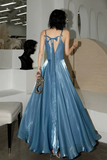 Woman in a blue evening gown standing in a modern indoor setting.