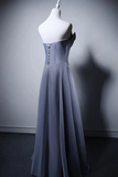 Gray evening gown on a mannequin against a plain background