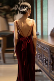 Woman in a red dress with a low back, standing in an elegant interior setting.