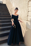 Woman in a dark blue evening gown standing on steps against a textured wall.