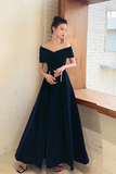 Woman in a navy off-shoulder gown standing indoors.