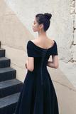 Woman in a black dress standing on steps with a textured wall background