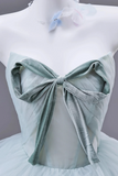 Mannequin wearing a light blue dress with a large bow detail on a plain background