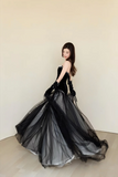 Woman in a black evening gown with a plain background