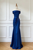 Blue evening gown on a mannequin against a white paneled wall.