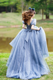 Woman in a blue dress standing outdoors by a pond