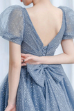 Blue polka dot dress with a deep neckline and bow detail on a white background