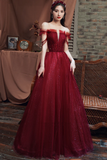 Woman in a red evening gown standing in front of a brick wall and draped fabric.