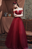 Woman in a red evening gown standing in a room with a brick wall and draped fabric.
