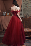 Woman in a red evening gown standing in front of a brick wall and draped fabric.