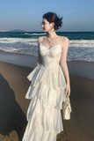Woman in a white dress standing on a beach with ocean waves in the background