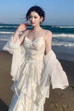 Woman in a white dress standing on a beach with ocean waves in the background
