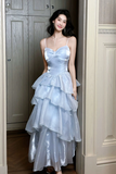 Woman in a light blue, tiered dress standing in a doorway.