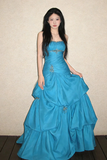 Woman wearing a blue evening gown against a plain background